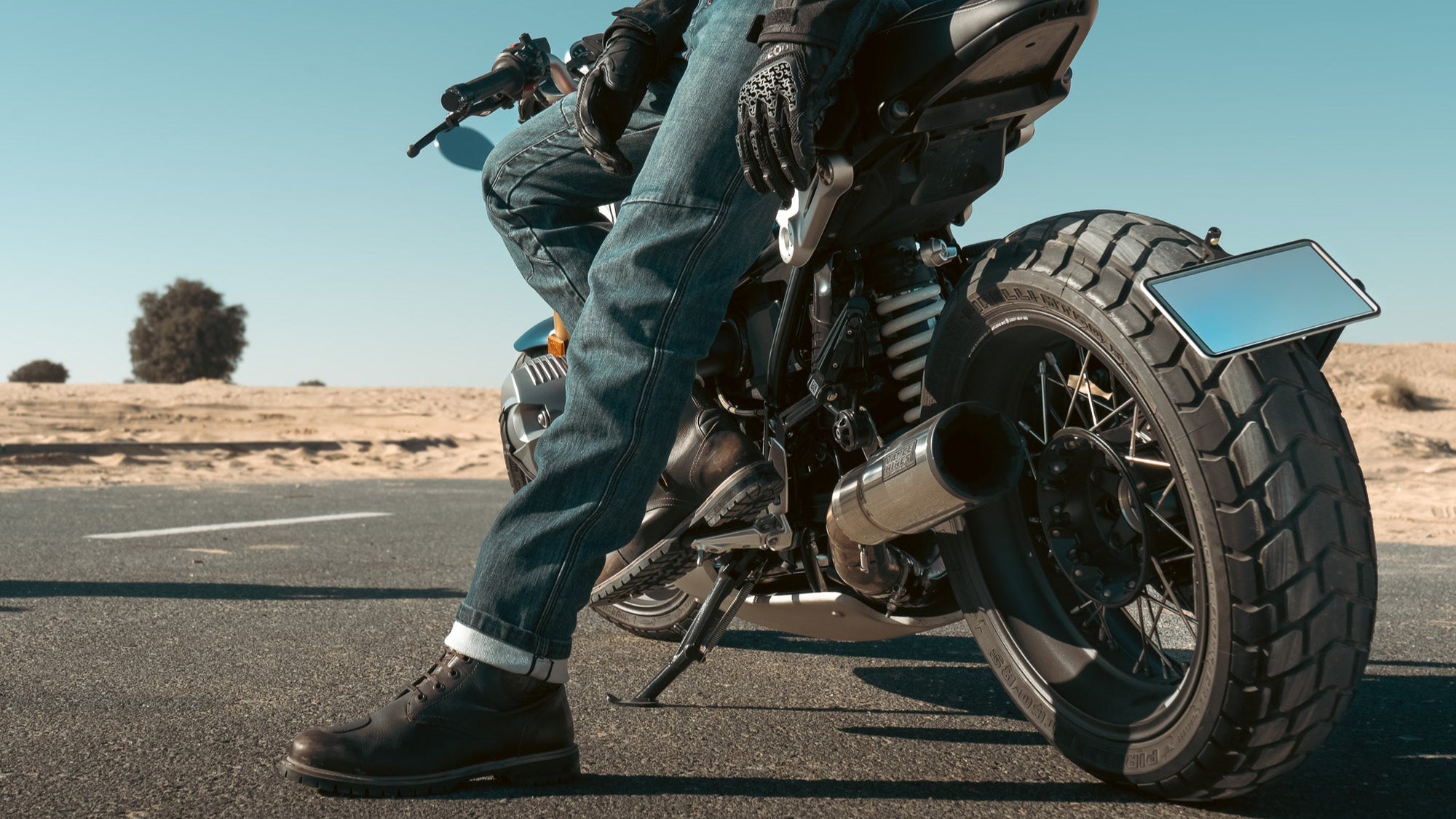 Person riding a motorcycle on a road with a clear sky